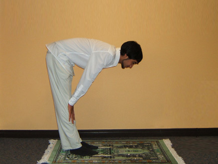 A man bows down so that his back is straight and his head faced down