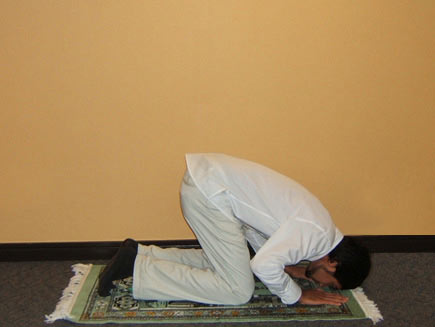 A man prostrates on the floor, with his hands beside his head